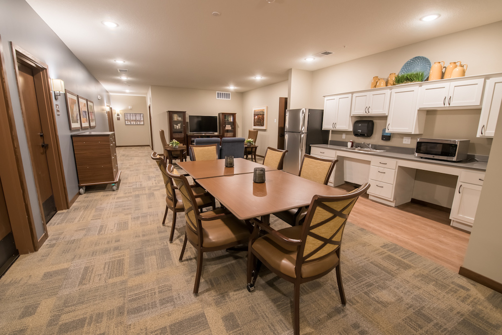 A comfortable community kitchen and lounge area in a residential facility with seating and appliances.