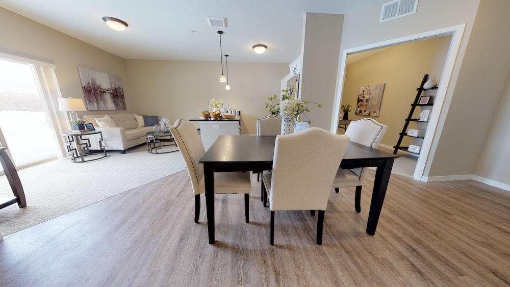 Modern open-concept living and dining area with wooden floors, beige walls, and contemporary furnishings.
