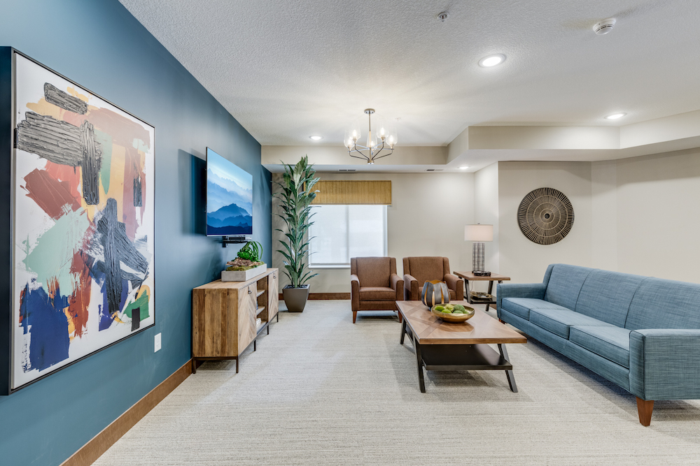Modern living room with blue accent wall, abstract art, and stylish furniture including a blue sofa.
