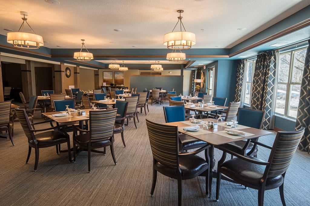 Communal dining room with multiple sets of tables and chairs.