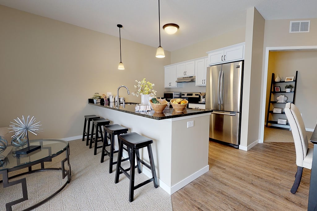 Kitchen with sleek appliances, bar, and barstools.